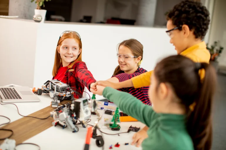 Students fist bump robotics class at Love to Code Academy