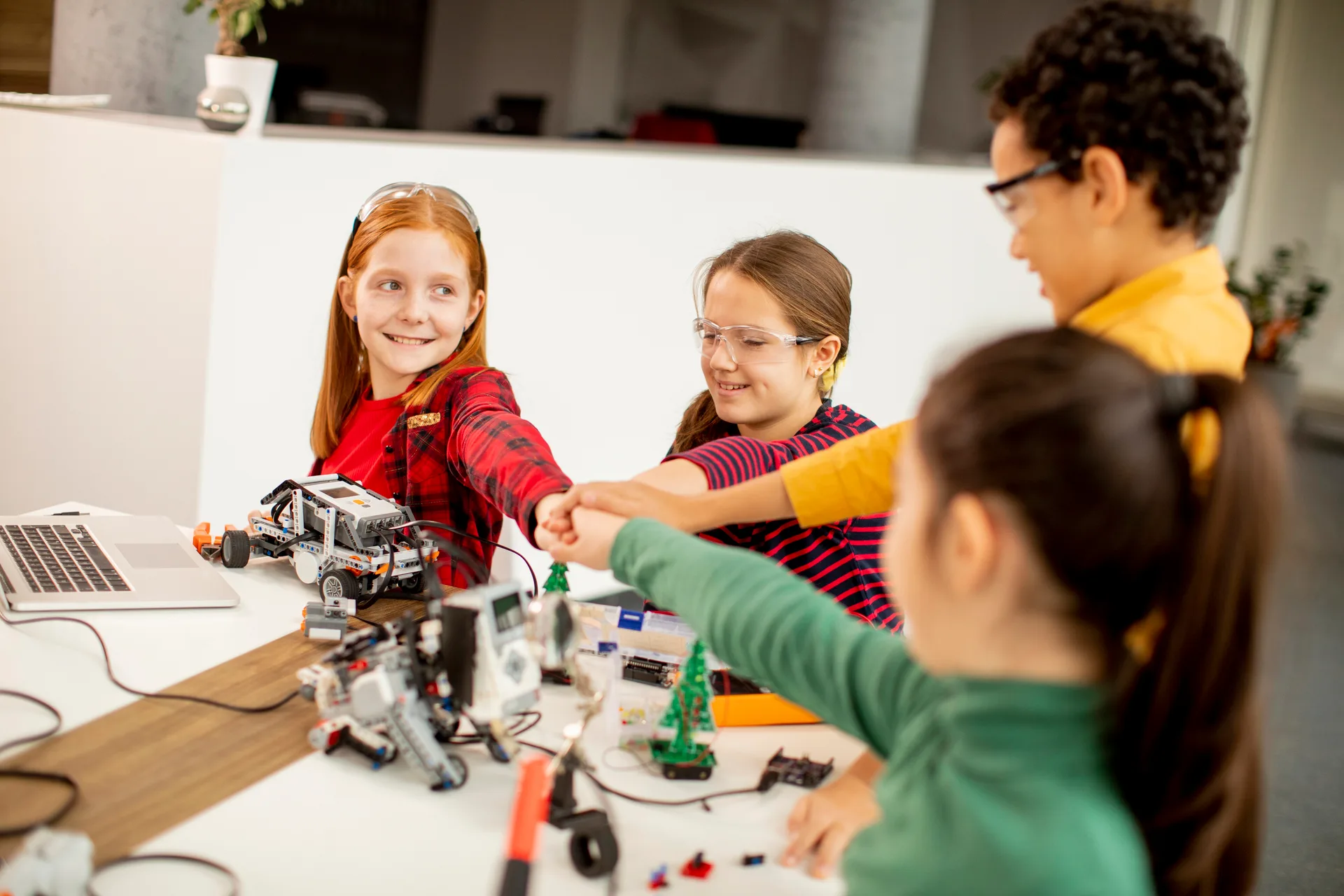 Students fist bump robotics class at Love to Code Academy