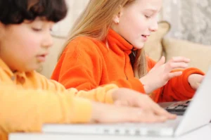 Students laptops orange sweaters at Love to Code Academy