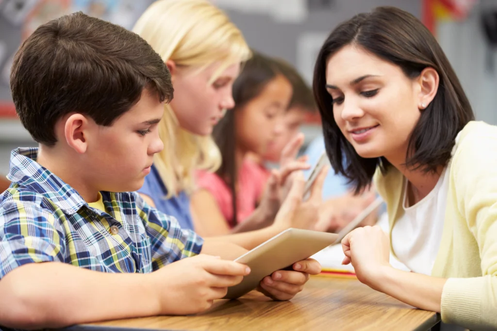 Coach reviewing a student's work with him on a tablet in class